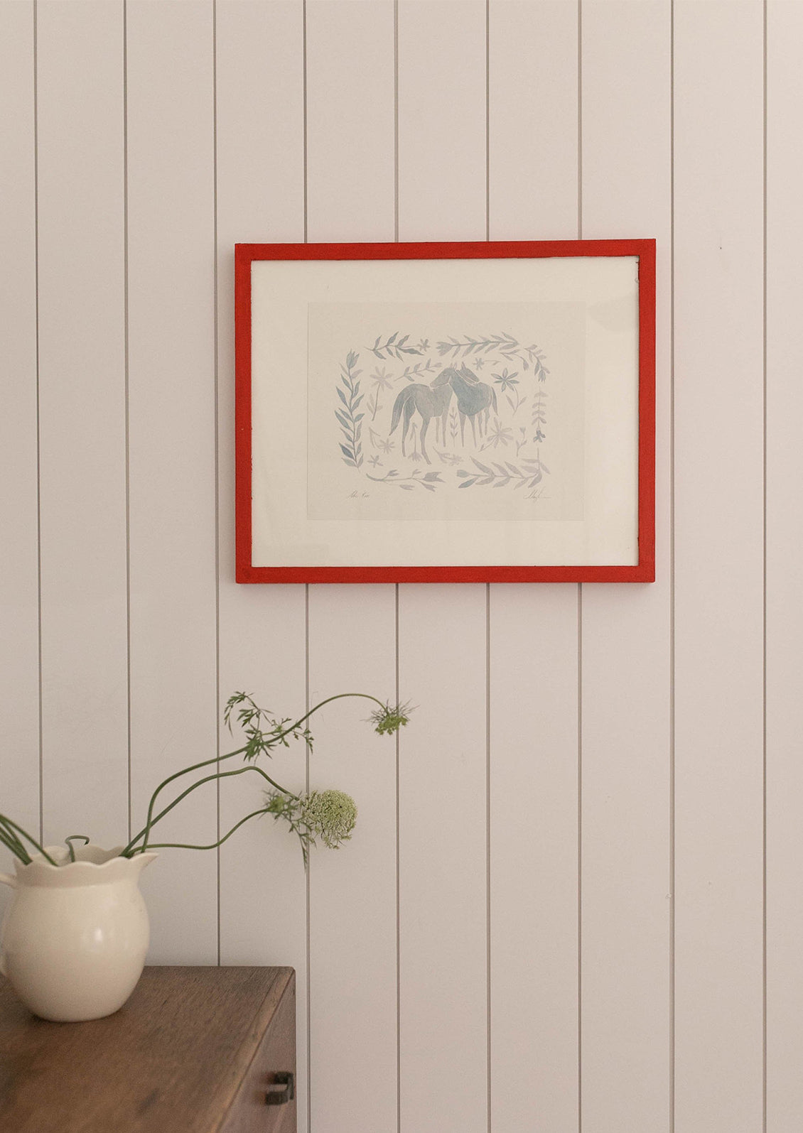 An art print of watercolor painting of two horses surrounded by floral frame in light blue.