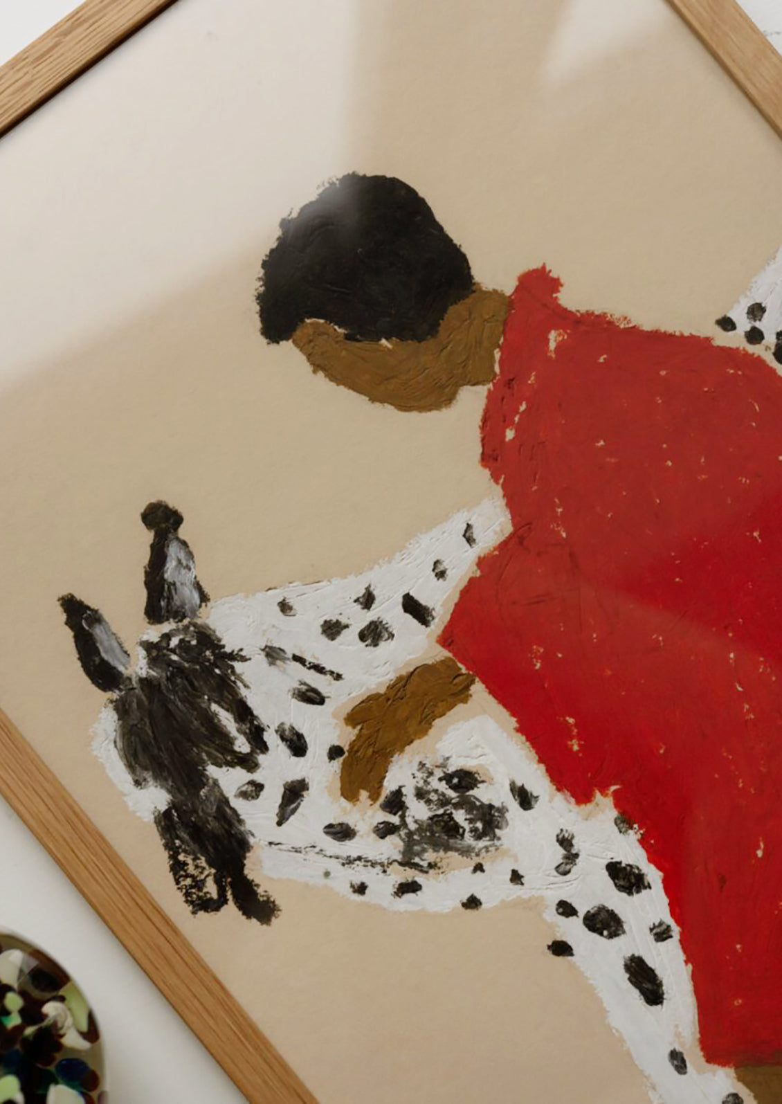 An art print of a painting of a woman with dark skin wearing a red jacket, petting a black and white spotted horse.