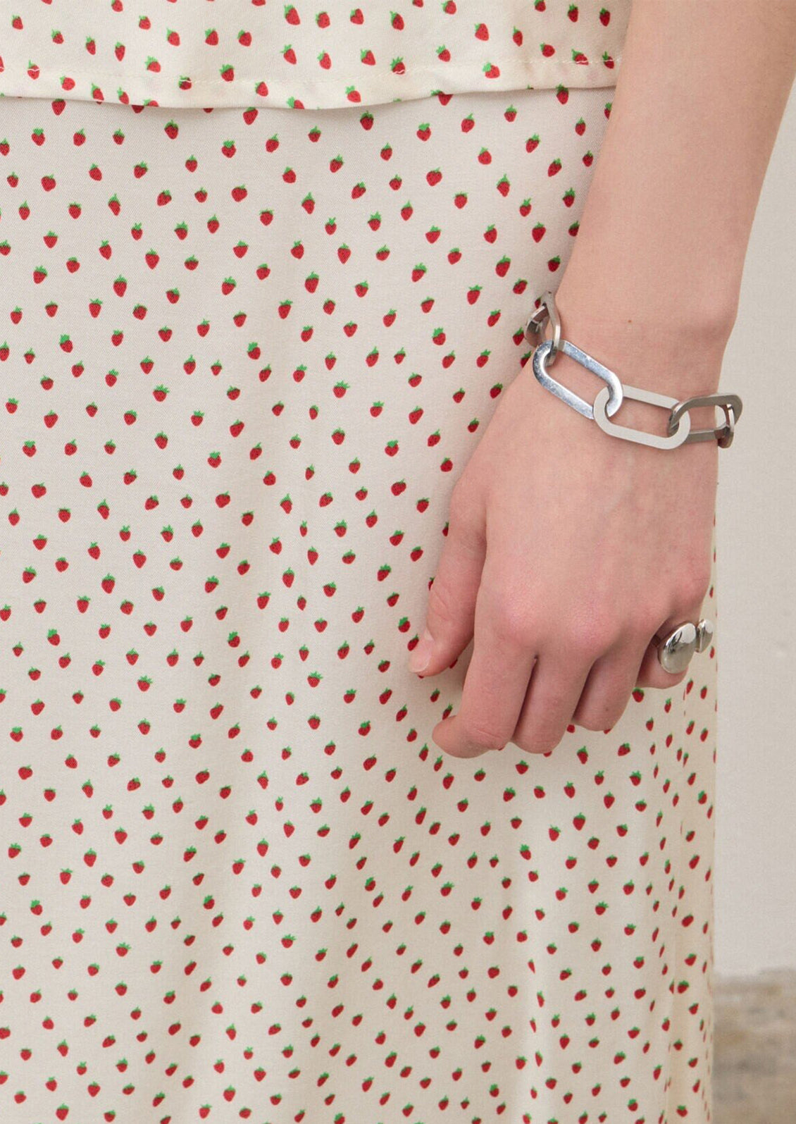 A person wearing an ivory slip skirt with small red strawberry print.