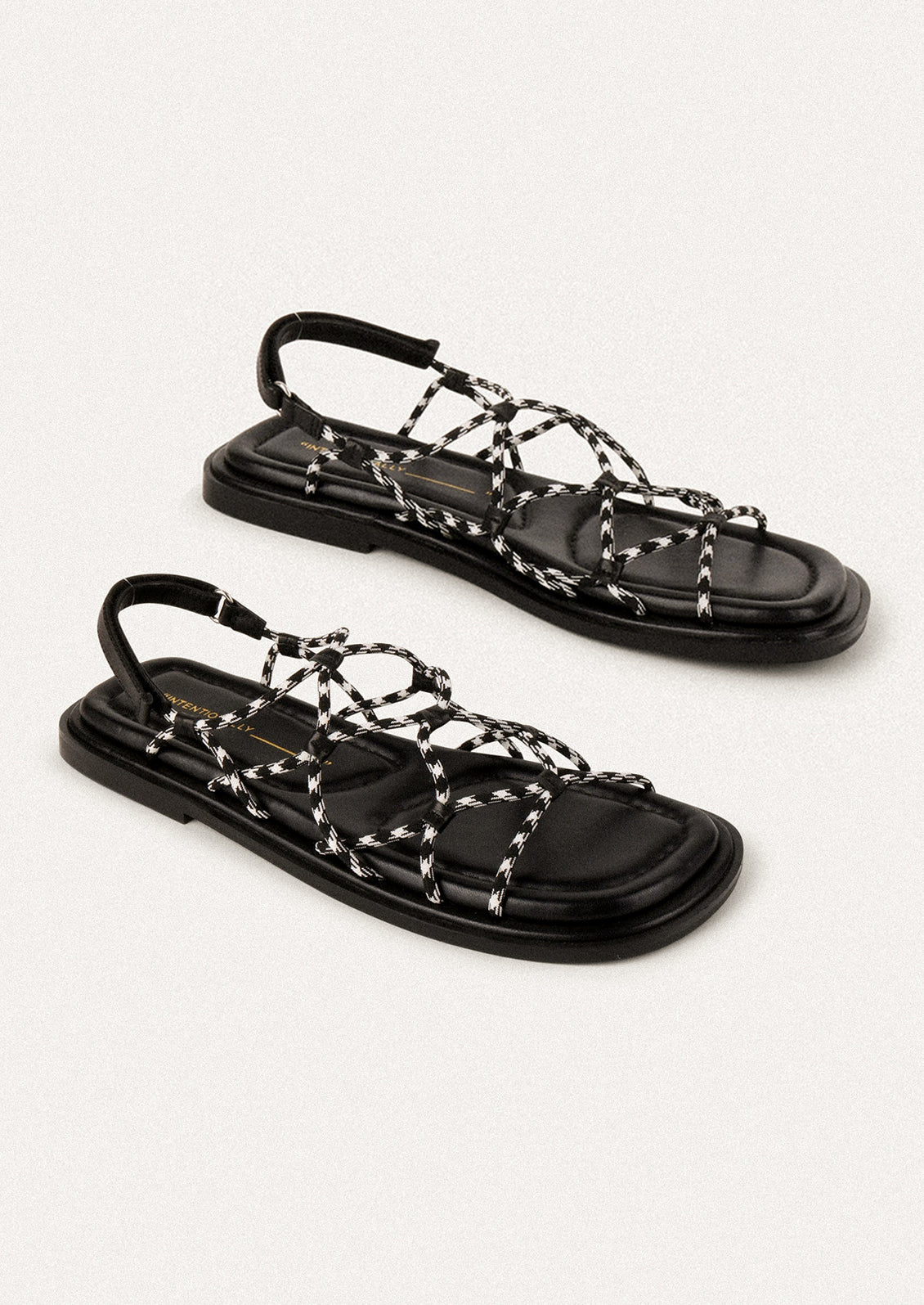 A pair of flat sandals with black and white paracord upper.