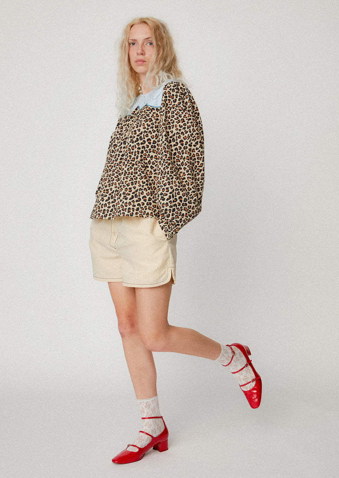 A woman wearing a leopard print blouse with light blue contrast yoke detail.