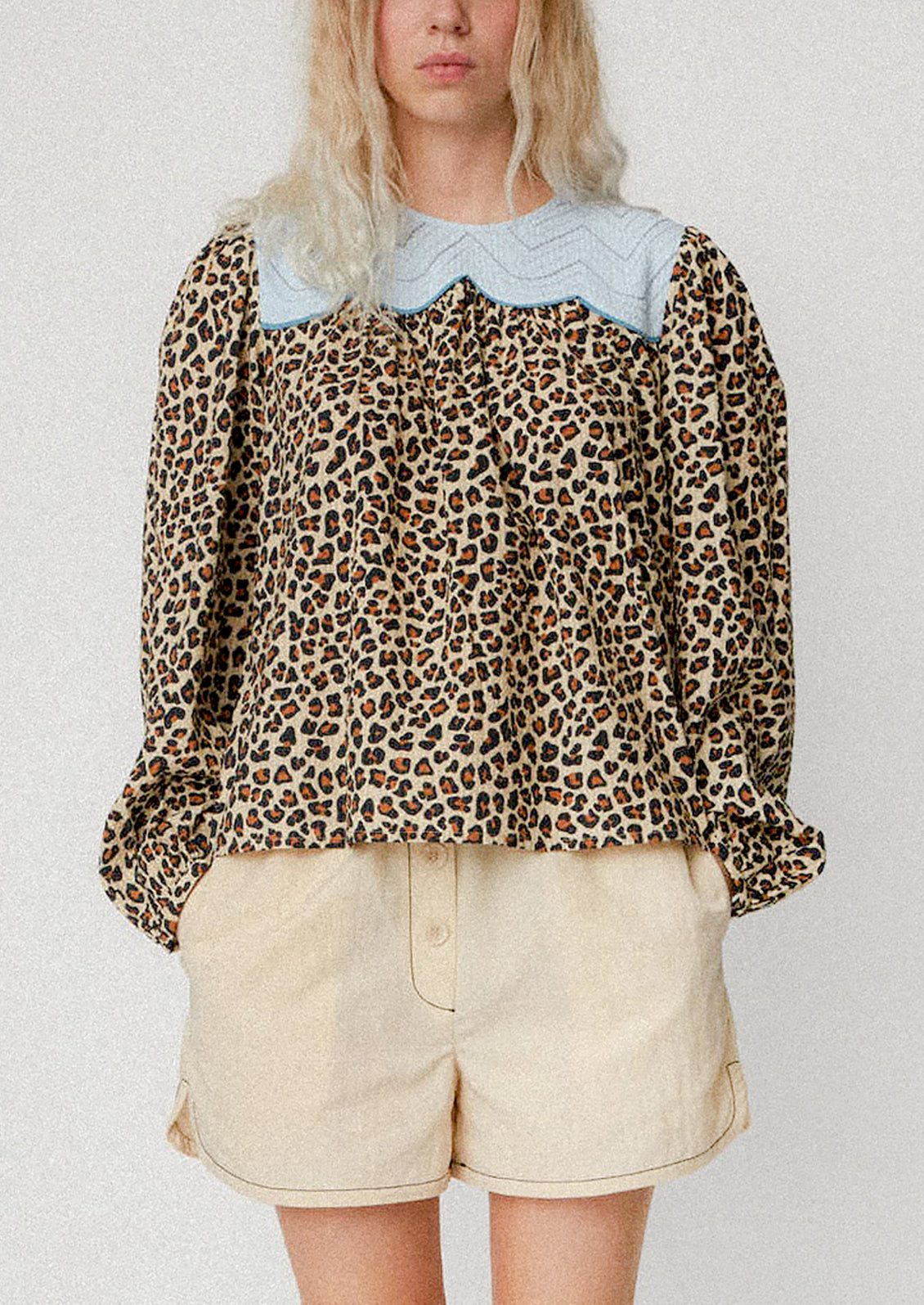 A woman wearing a leopard print blouse with light blue contrast yoke detail.