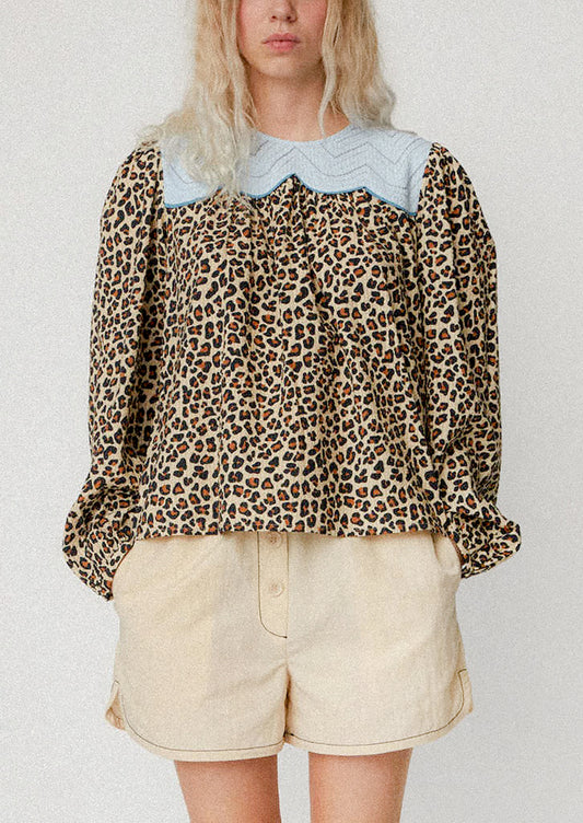 A woman wearing a leopard print blouse with light blue contrast yoke detail.