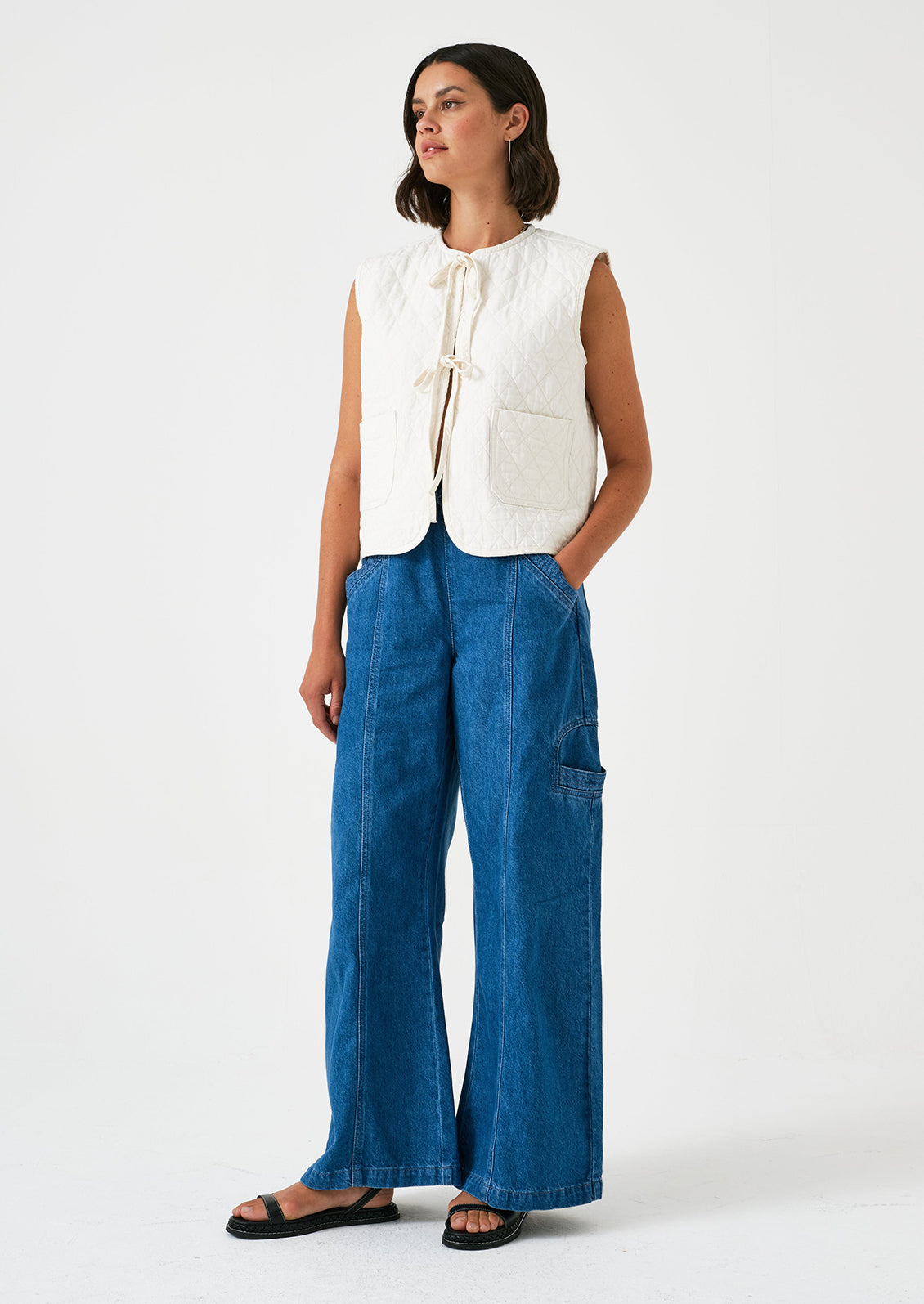 A woman wearing a pair of relaxed leg pants with cargo style details, in bright blue denim.