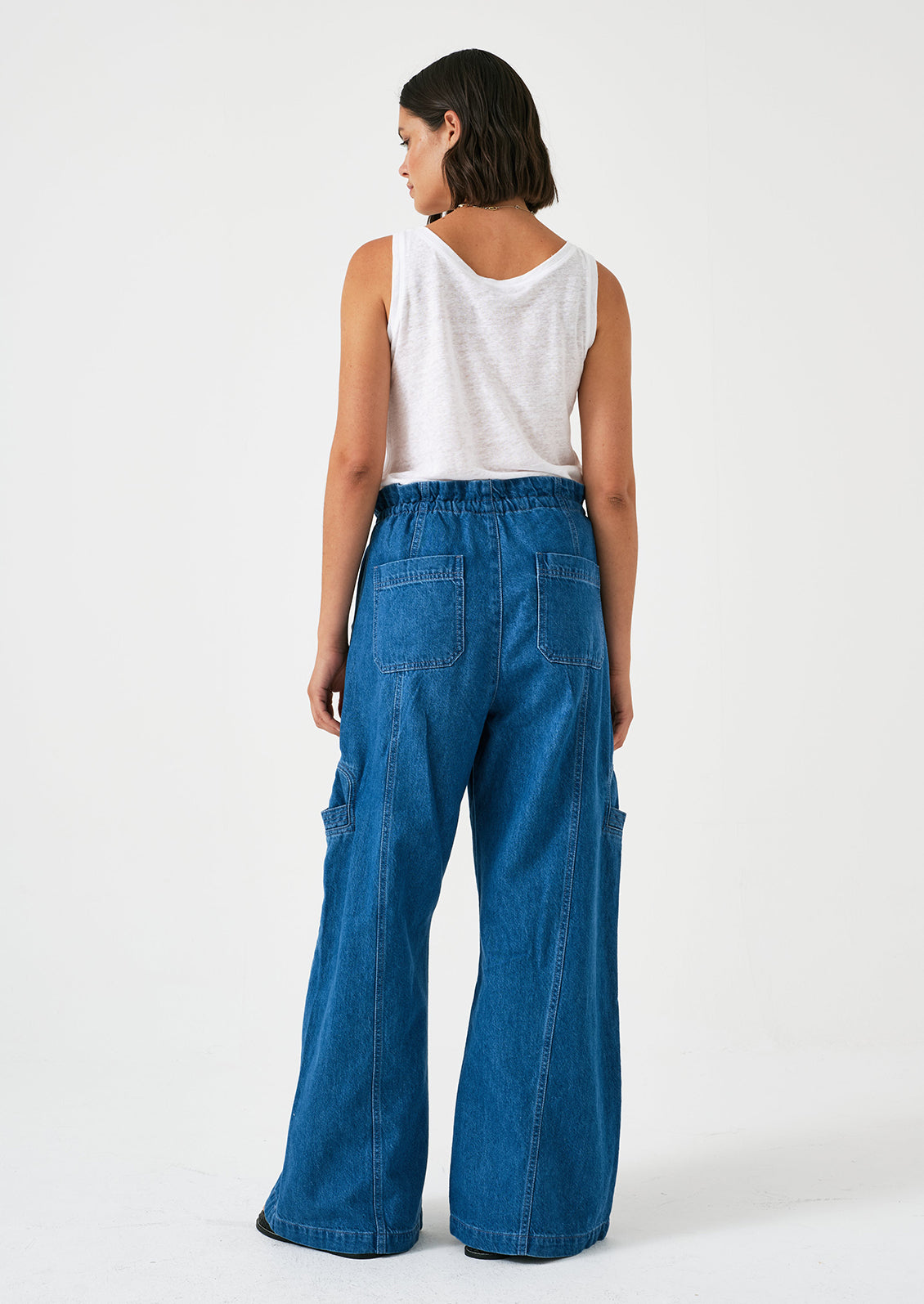 A woman wearing a pair of relaxed leg pants with cargo style details, in bright blue denim.