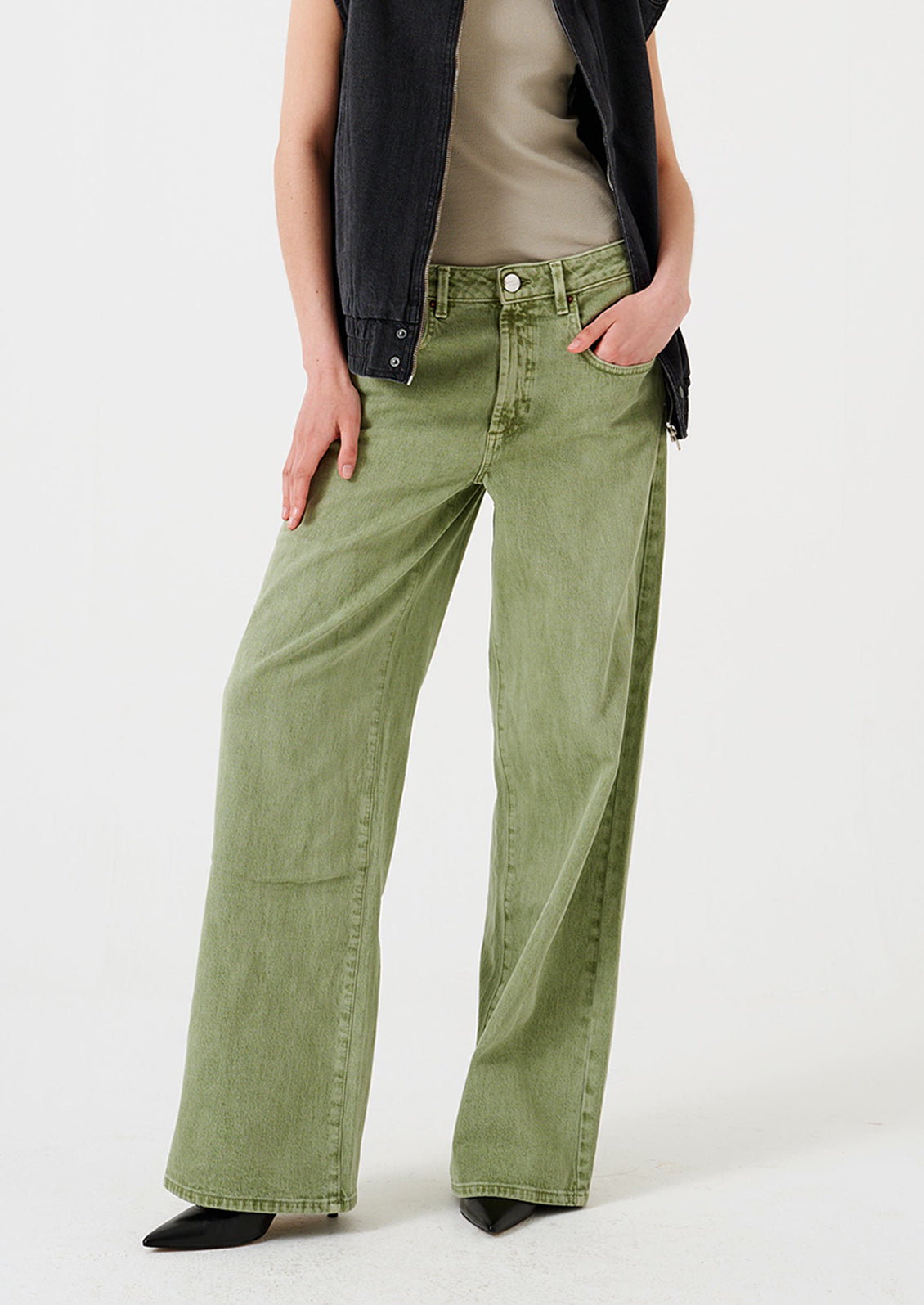 A woman wearing a pair of wide leg jeans in moss green wash.