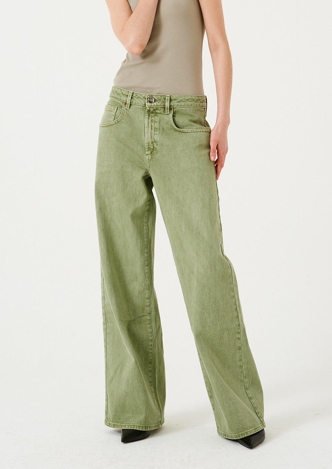 A woman wearing a pair of wide leg jeans in moss green wash.