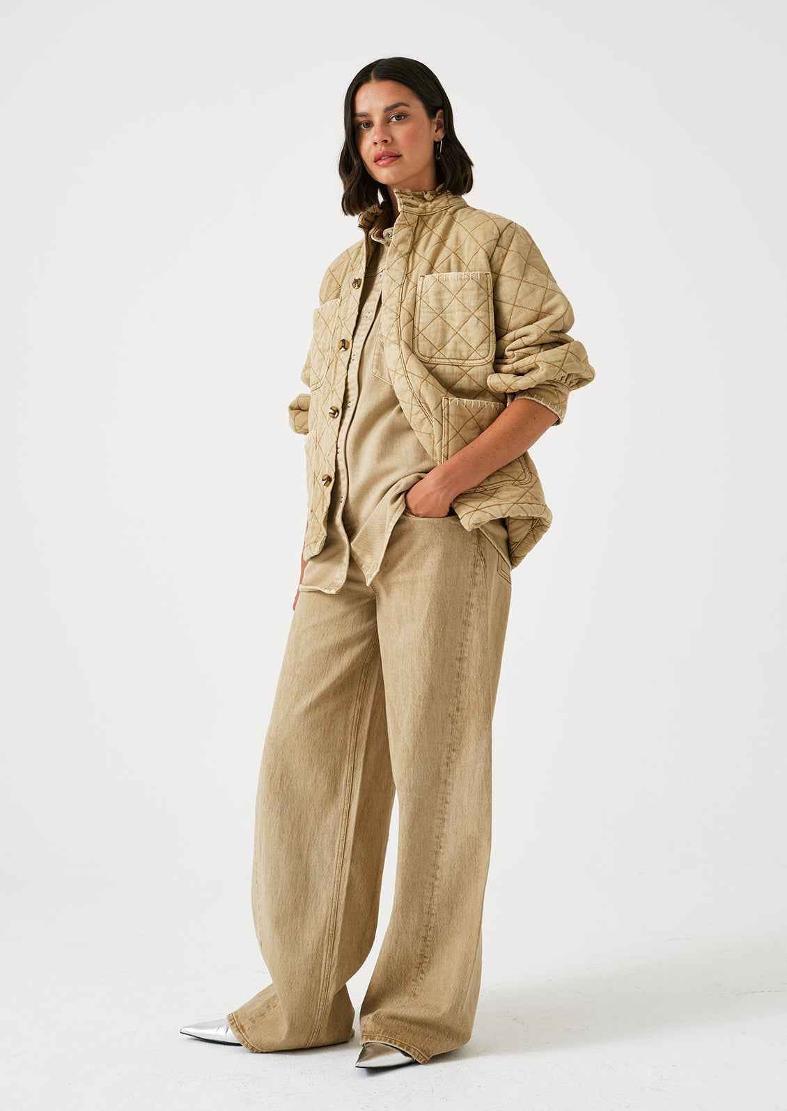 A woman wearing a pair of slouchy wide leg jeans in a stonewashed sand color.