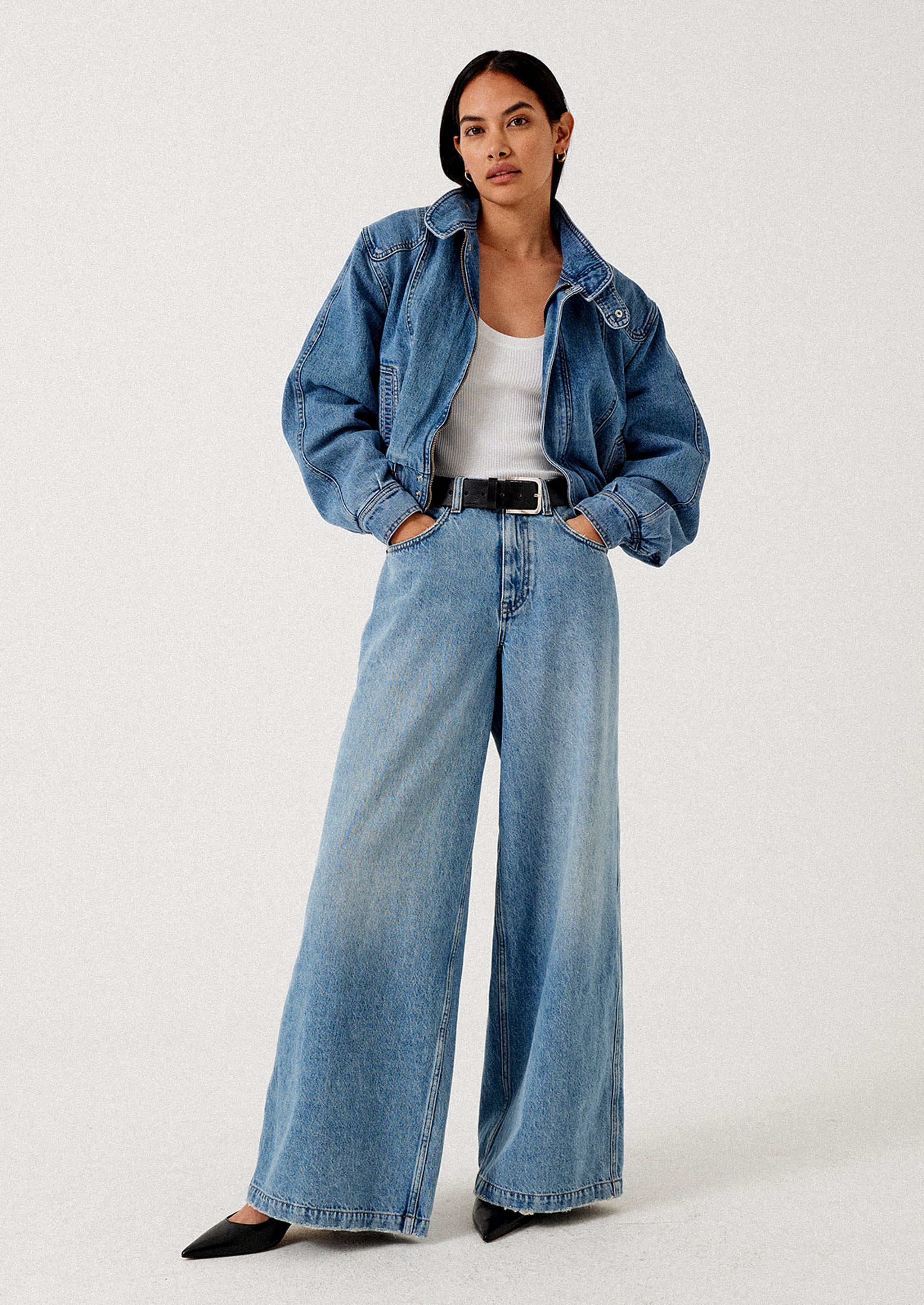 A person wearing a pair of medium wash wide leg jeans.