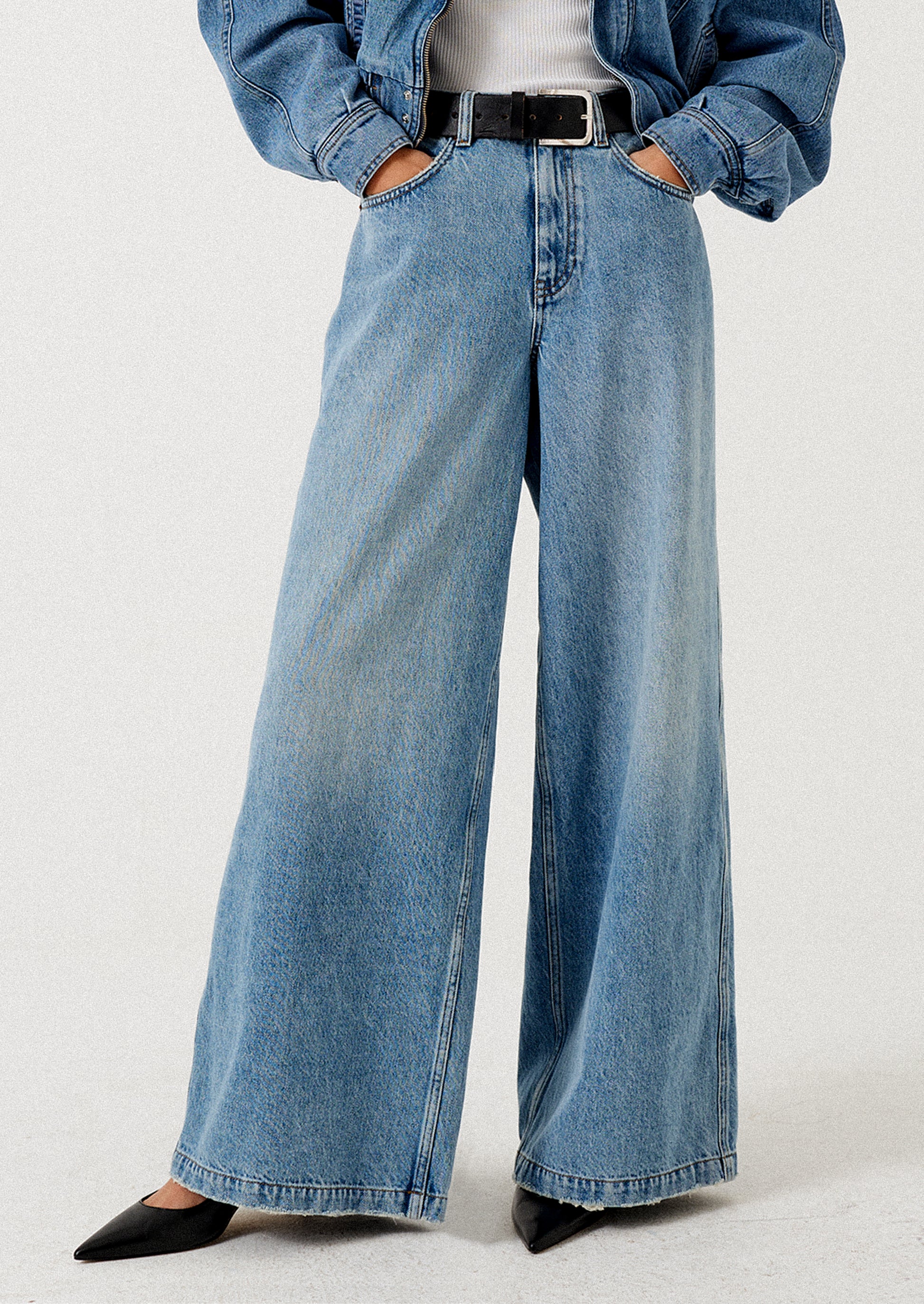 A person wearing a pair of medium wash wide leg jeans.