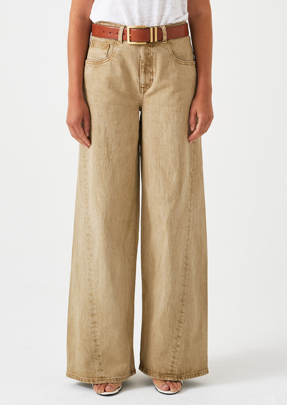 A woman wearing a pair of slouchy wide leg jeans in a stonewashed sand color.