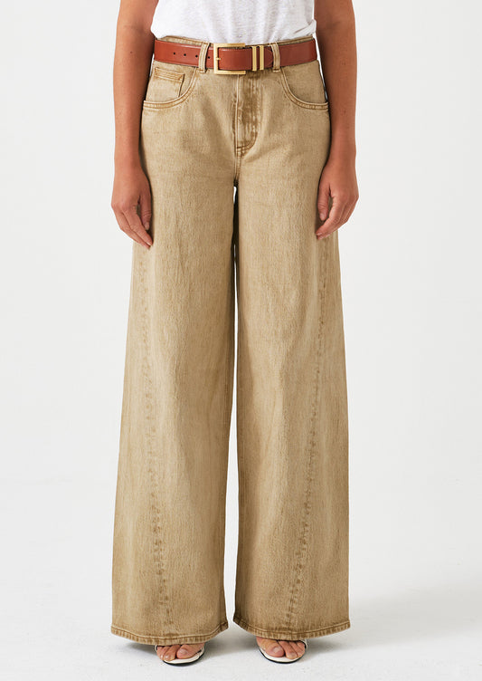A woman wearing a pair of slouchy wide leg jeans in a stonewashed sand color.