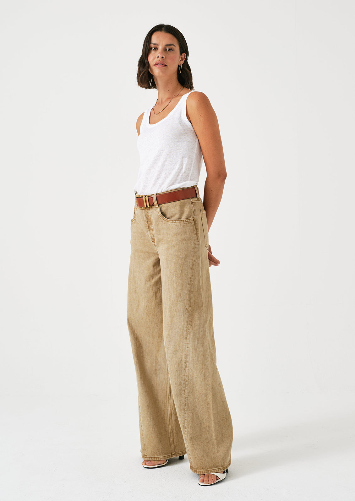 A woman wearing a pair of slouchy wide leg jeans in a stonewashed sand color.