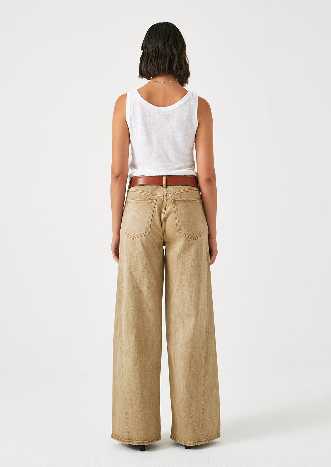 A woman wearing a pair of slouchy wide leg jeans in a stonewashed sand color.