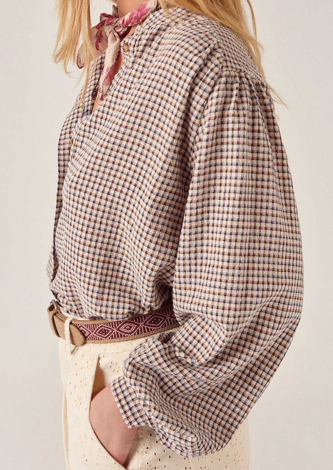 A person wearing a long sleeve blouse in brown check.