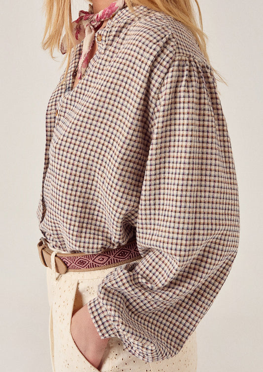 A person wearing a long sleeve blouse in brown check.
