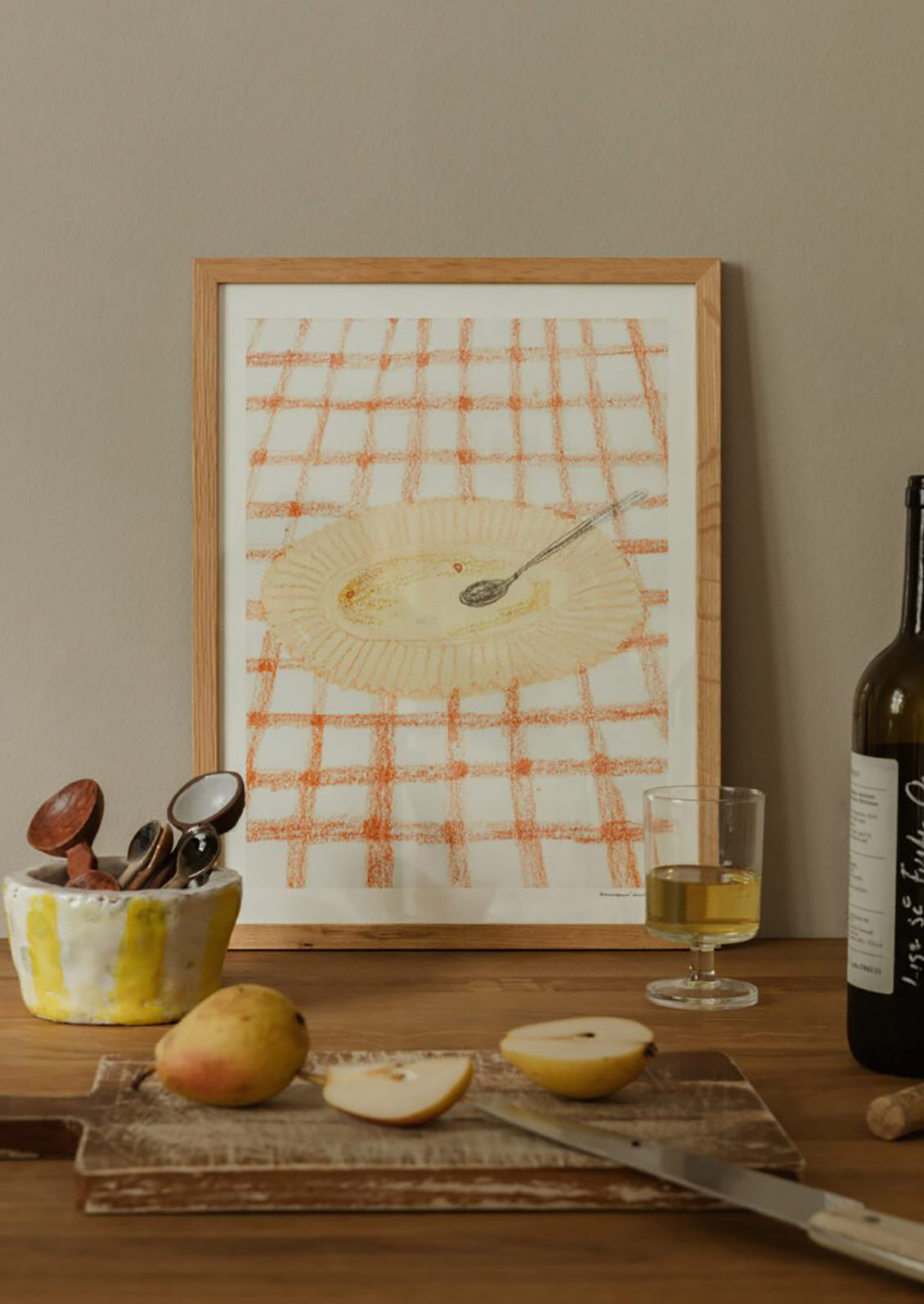 An art print of a drawing of a yellow plate on an orange and white checkered surface.