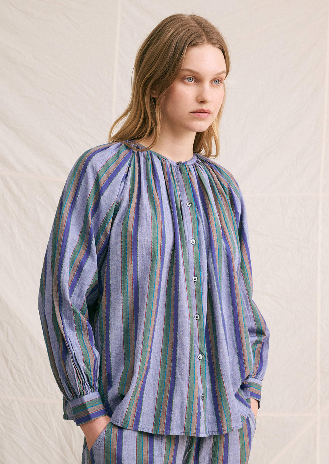 A woman wearing a blue chambray blouse with green and brown stripe pattern.