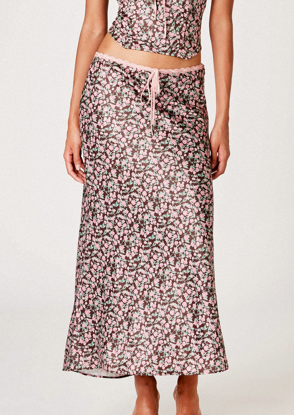 A woman wearing a brown satin skirt with pink floral print.