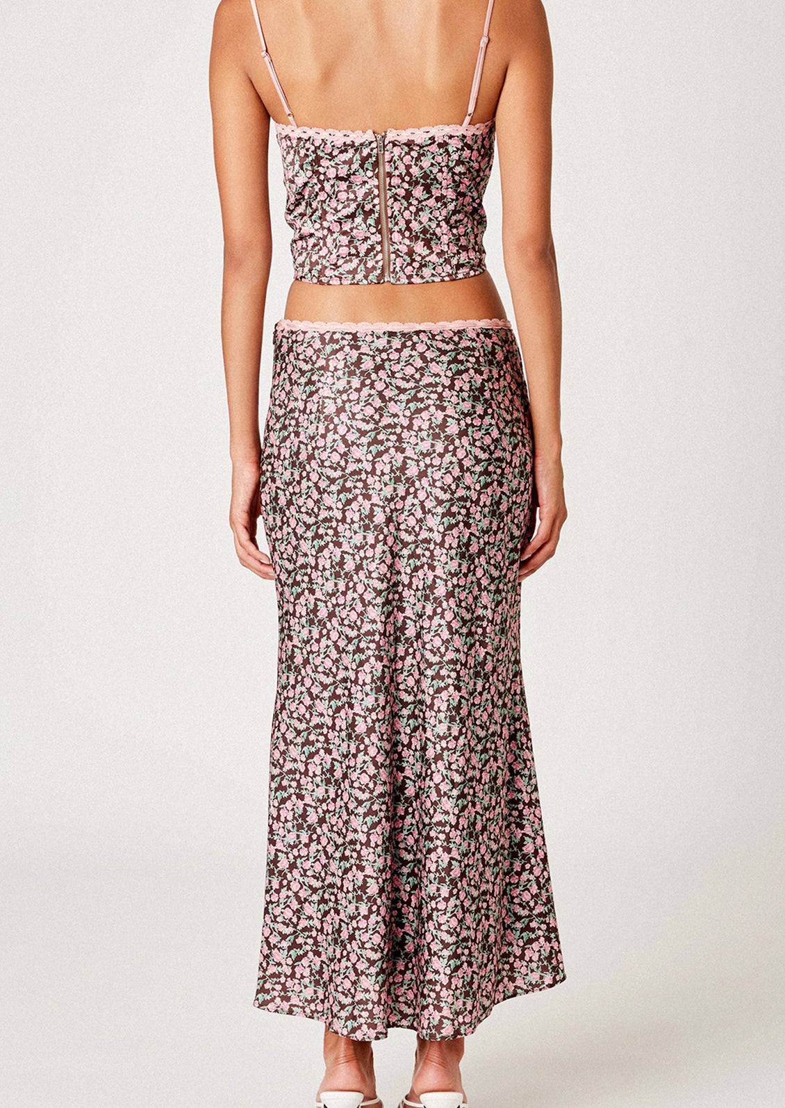 A woman wearing a brown satin skirt with pink floral print.