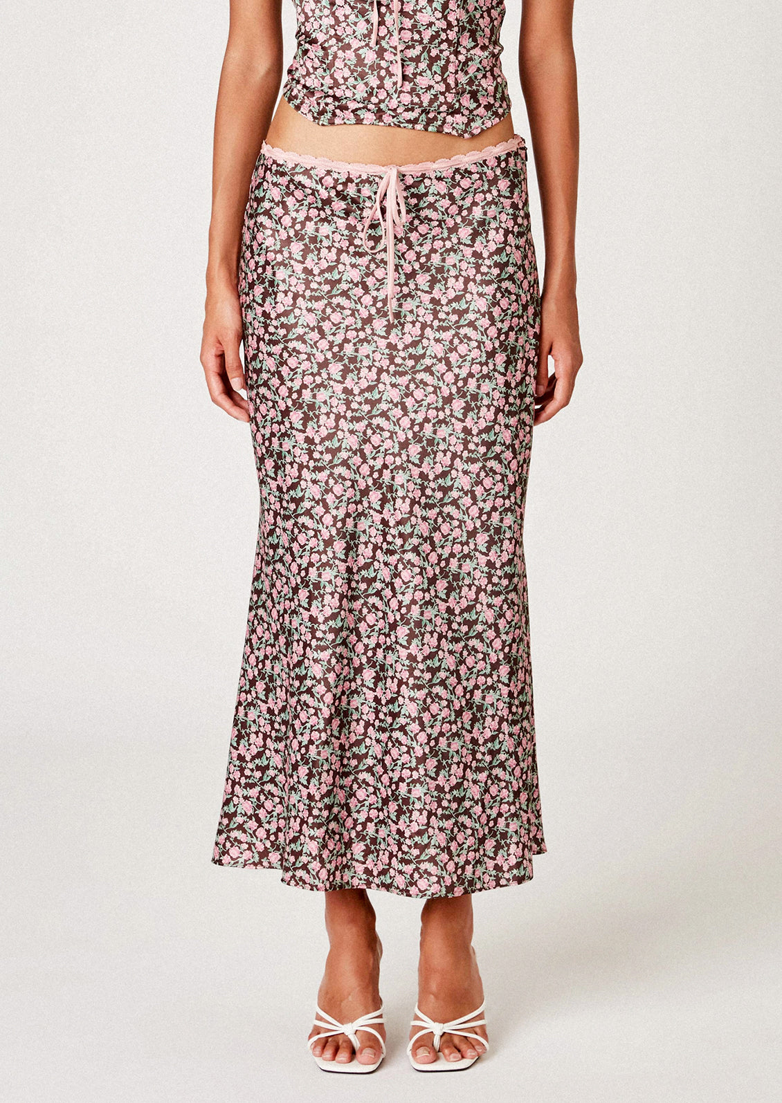 A woman wearing a brown satin skirt with pink floral print.