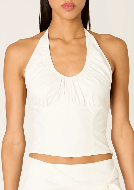 A person wearing a sleeveless scoop neck halter top in white.