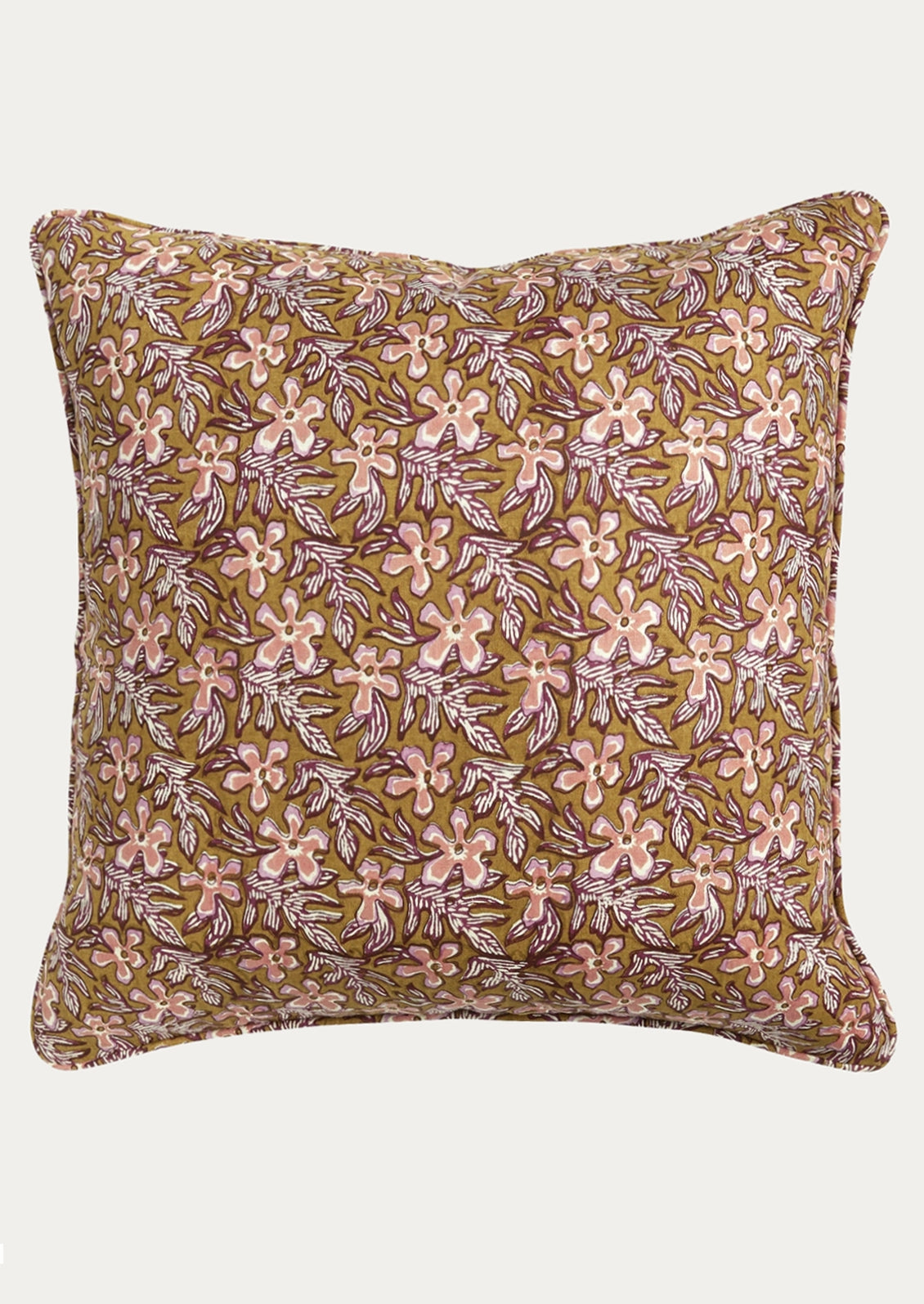 A square decorative throw pillow featuring an all-over floral block print pattern in pink and purple on a warm olive-brown background, shown against a plain light gray studio backdrop.
