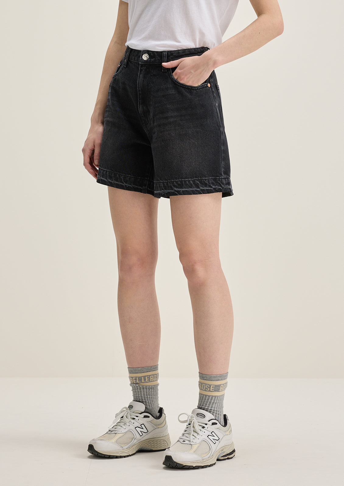 A person wearing a pair of wide leg denim shorts in charcoal wash.