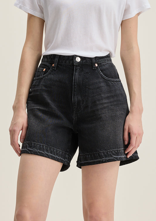 A person wearing a pair of wide leg denim shorts in charcoal wash.