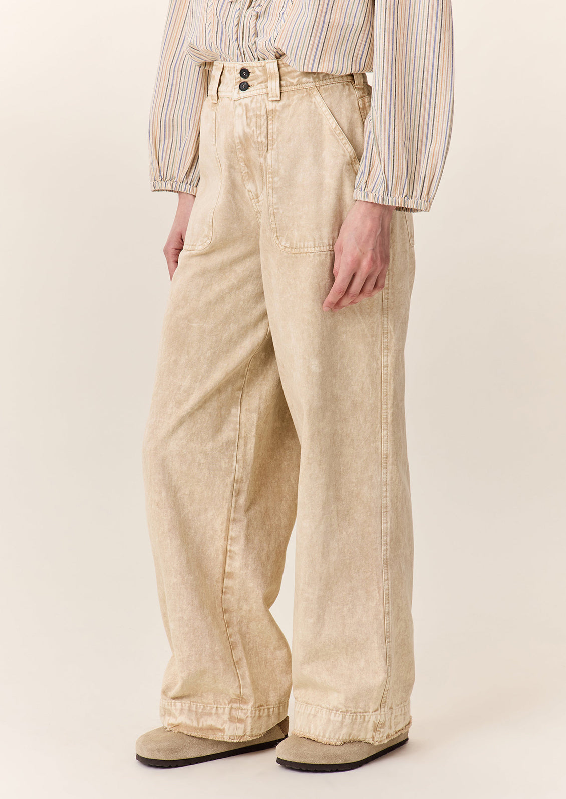 A person wearing a pair of wide leg pants in sand stonewash fabric.