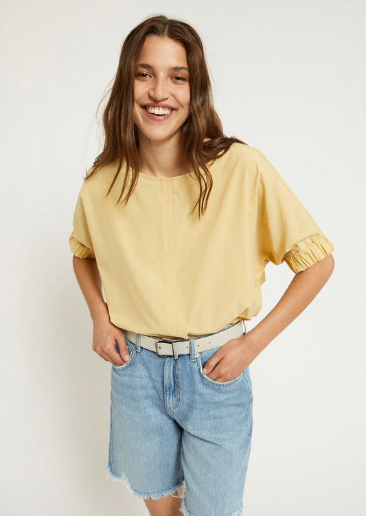 A woman wearing a short sleeve blouse in yellow color.
