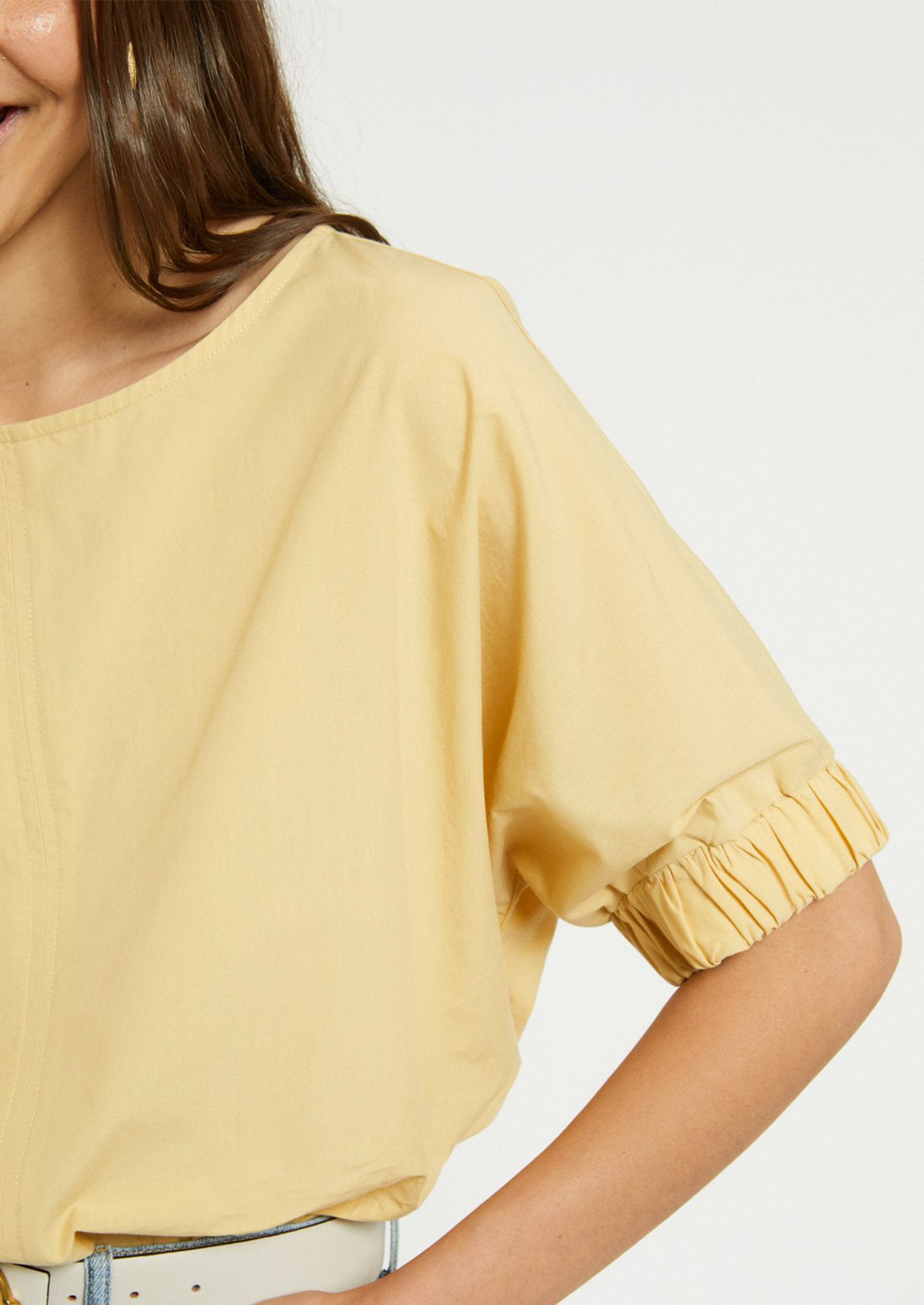 A woman wearing a short sleeve blouse in yellow color.