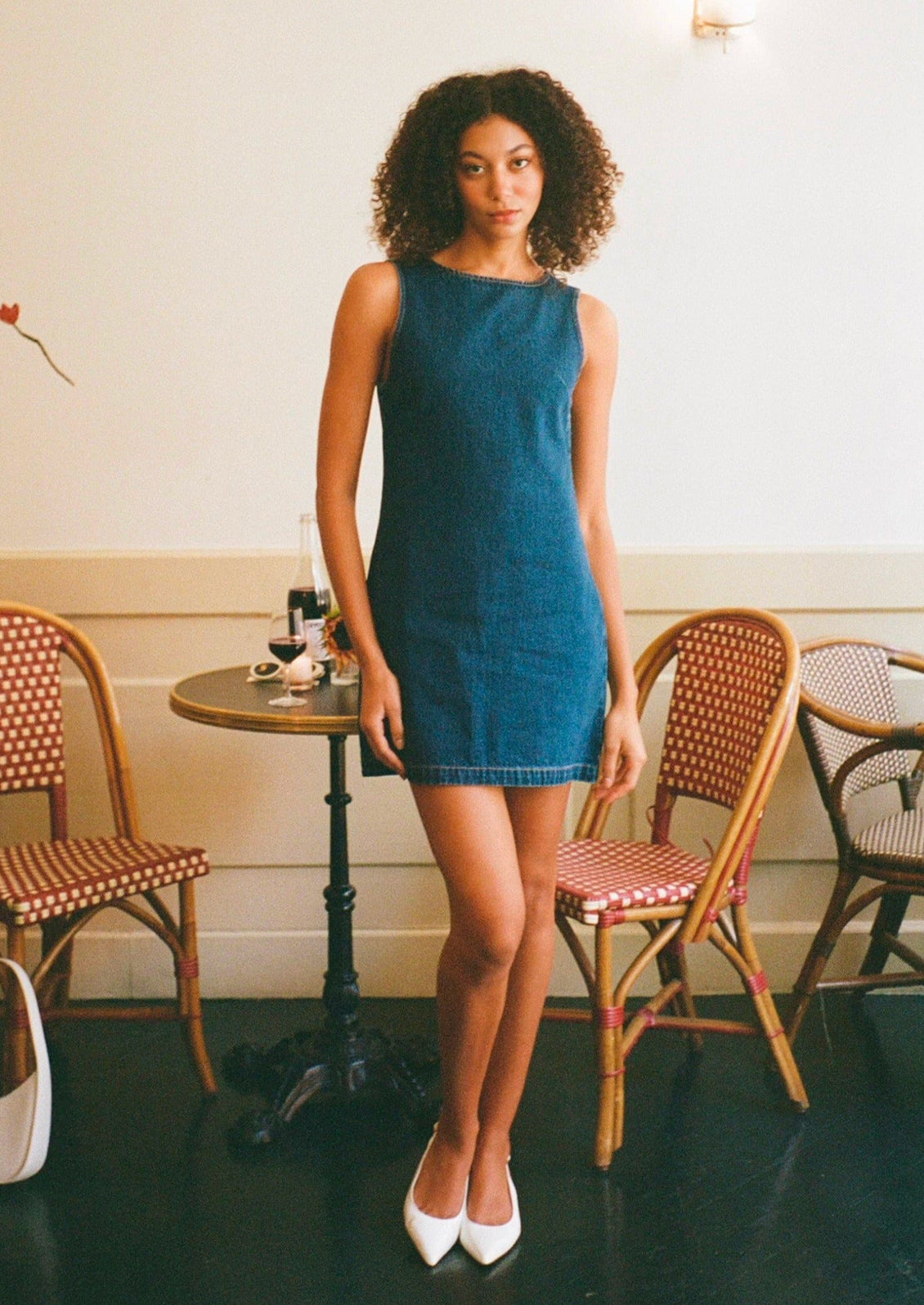 A woman wearing a short shift dress in dark blue denim.