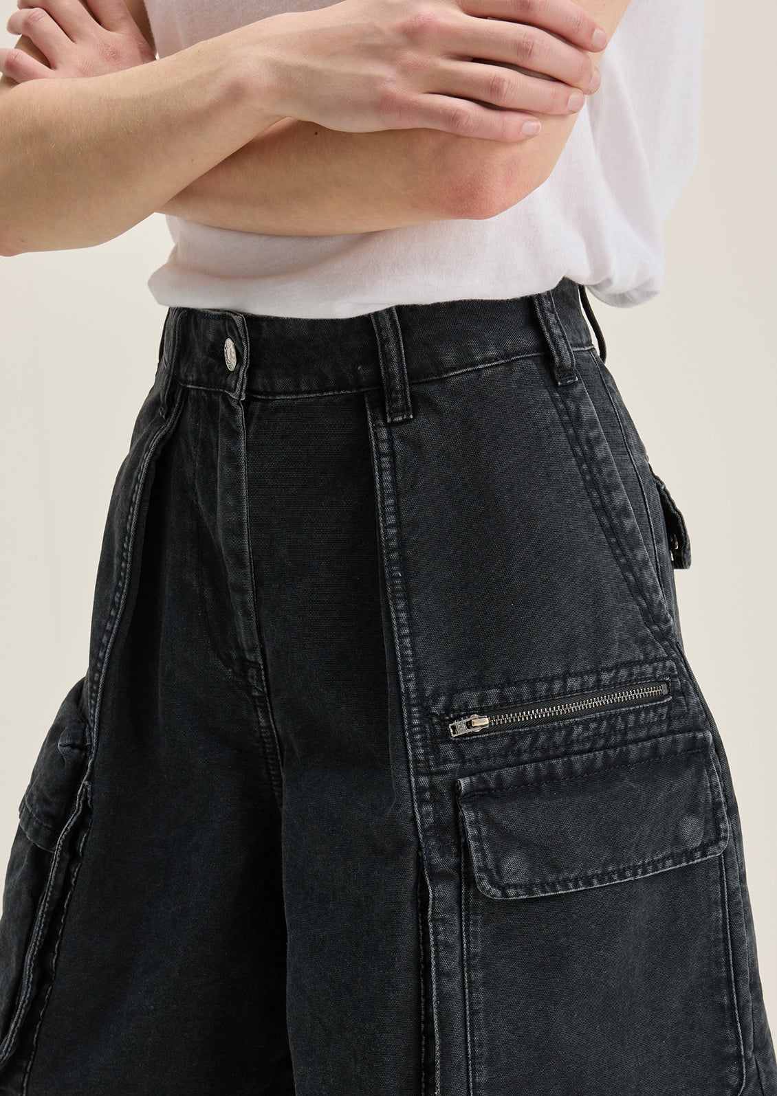 A person wearing a pair of charcoal denim cargo shorts.