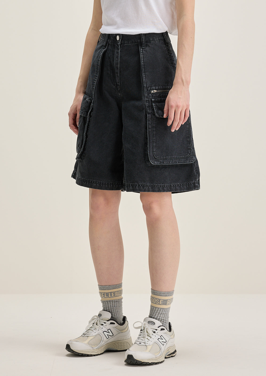 A person wearing a pair of charcoal denim cargo shorts.