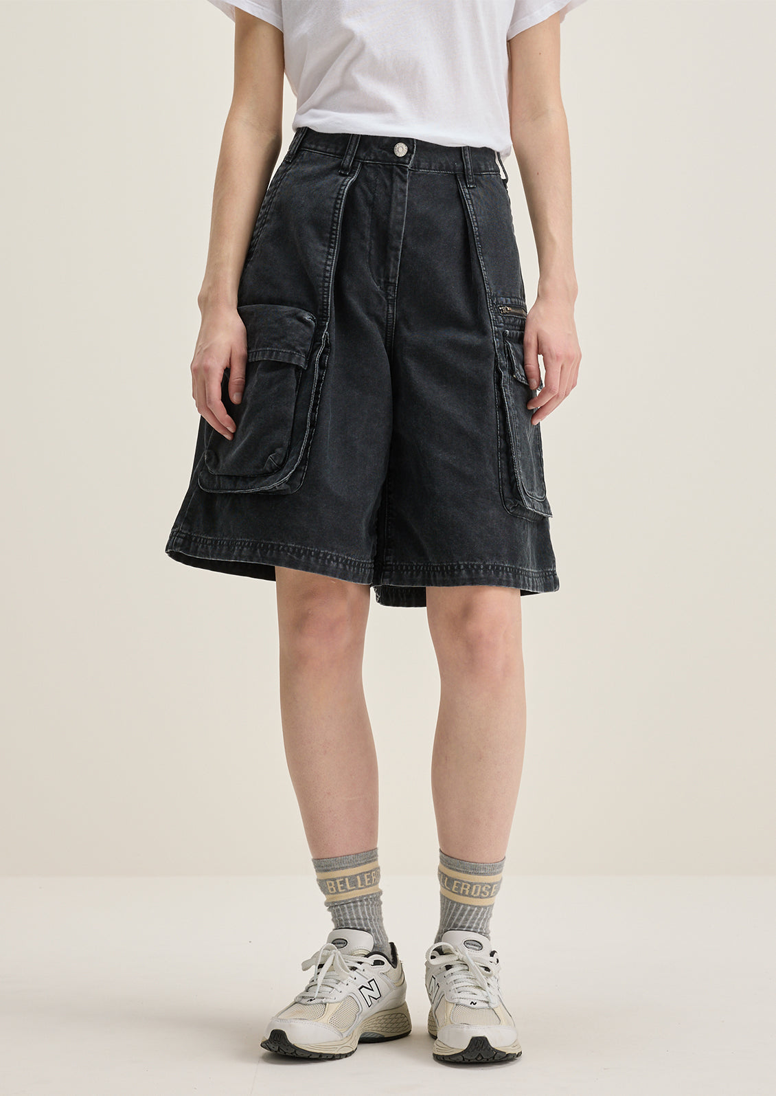 A person wearing a pair of charcoal denim cargo shorts.