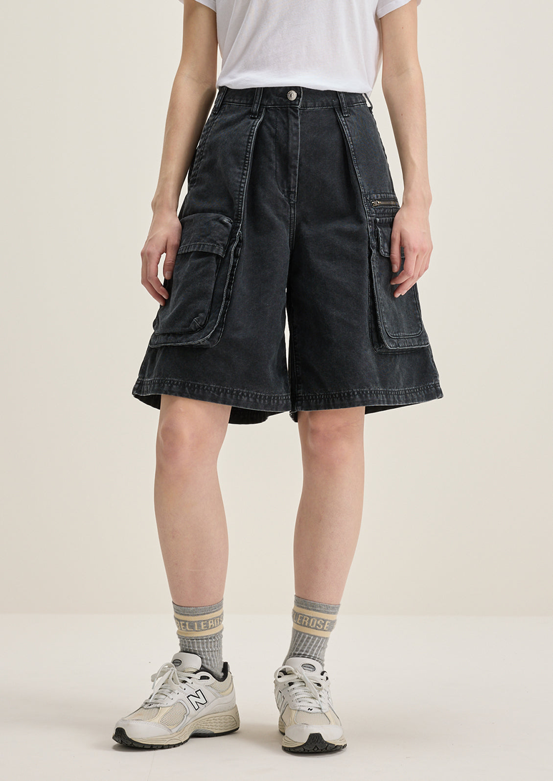 A person wearing a pair of charcoal denim cargo shorts.