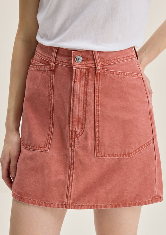A person wearing a mini skirt in coral colored denim.