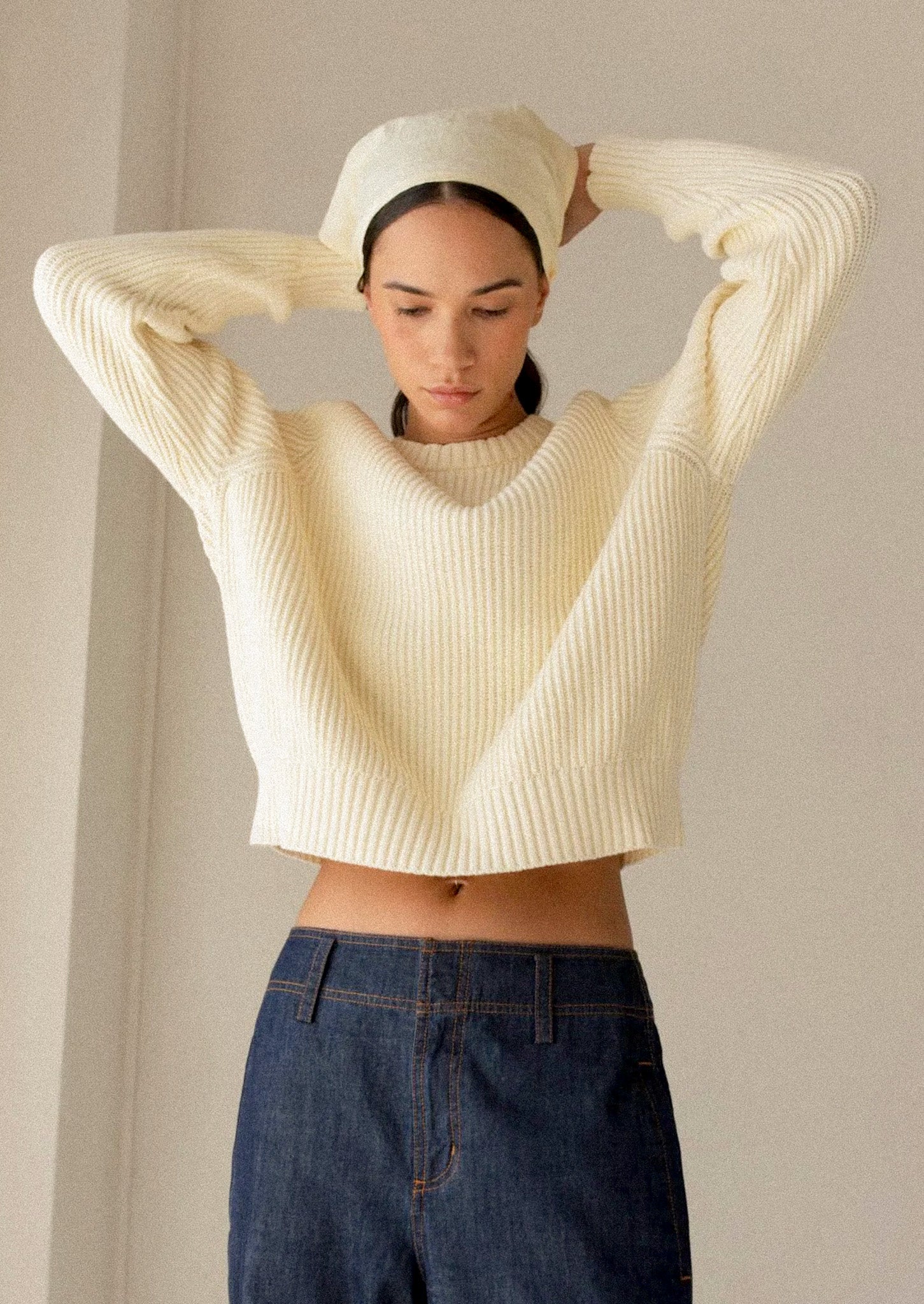 A woman wearing a rib knit sweater in pale yellow.