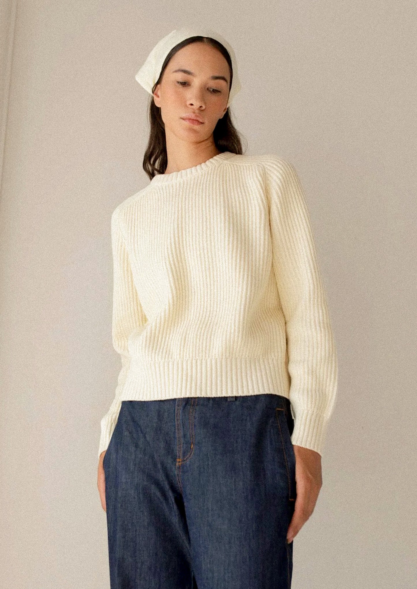 A woman wearing a rib knit sweater in pale yellow.