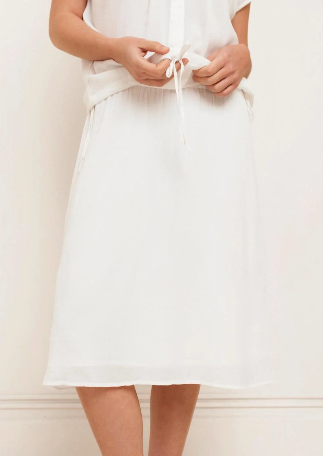 Person wearing a white dress against a plain background