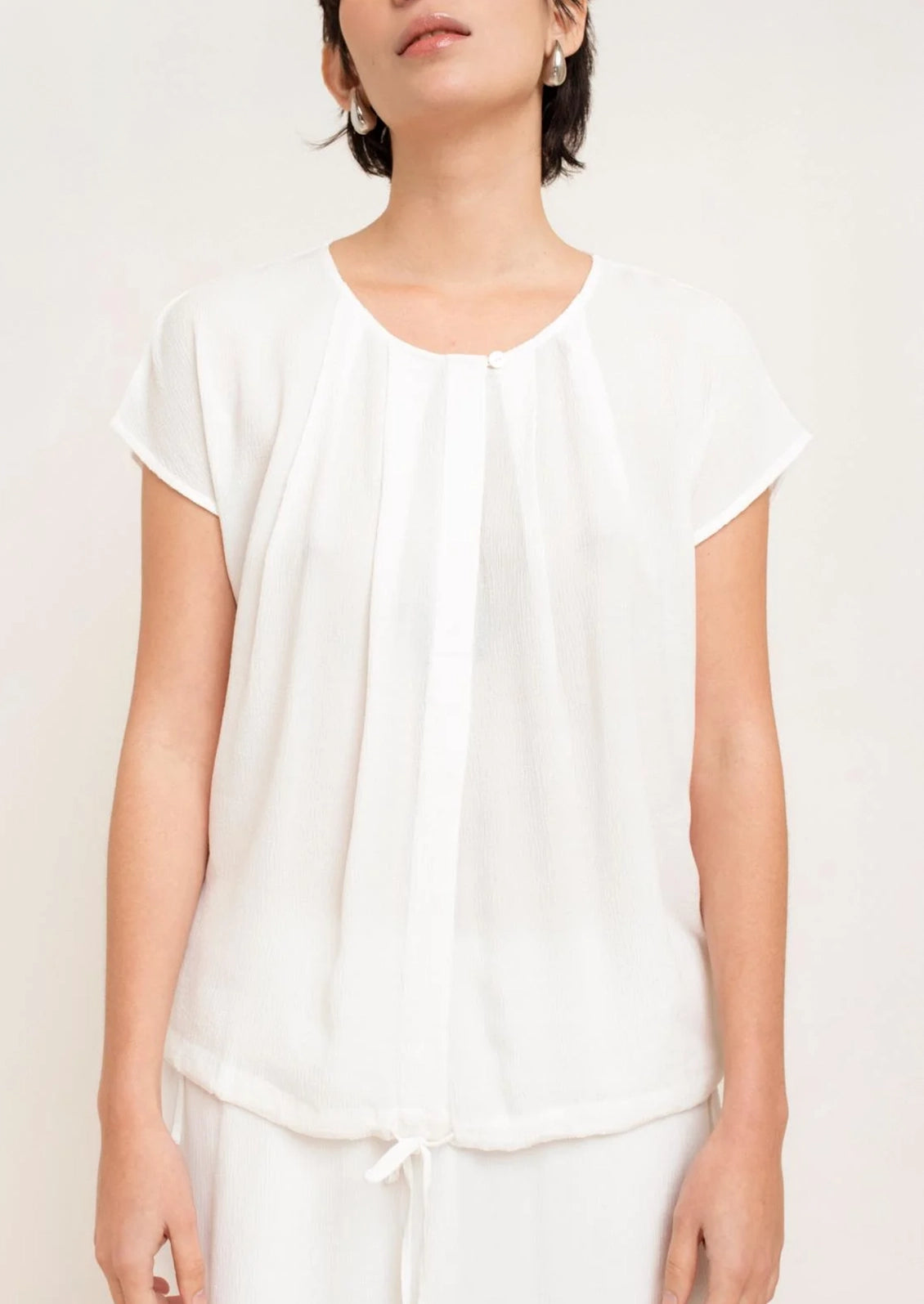 Person wearing a white top and pants on a plain background