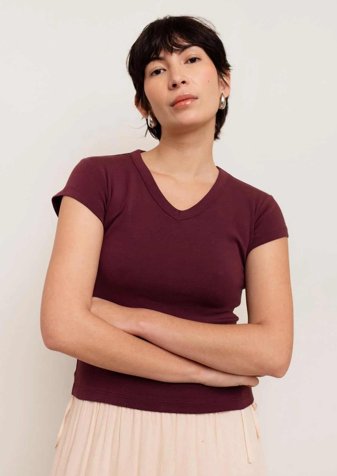 Woman wearing a maroon V-neck shirt against a plain background