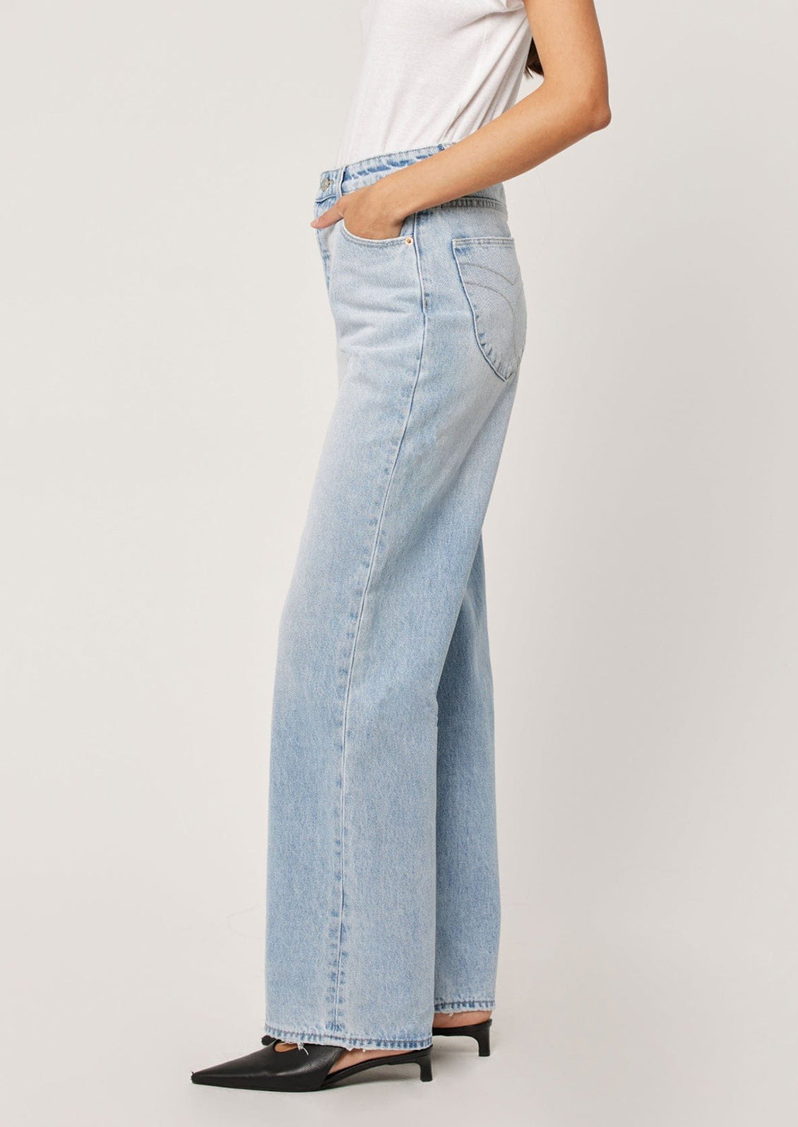 A person wearing a pair of straight leg relaxed jeans in light blue denim.