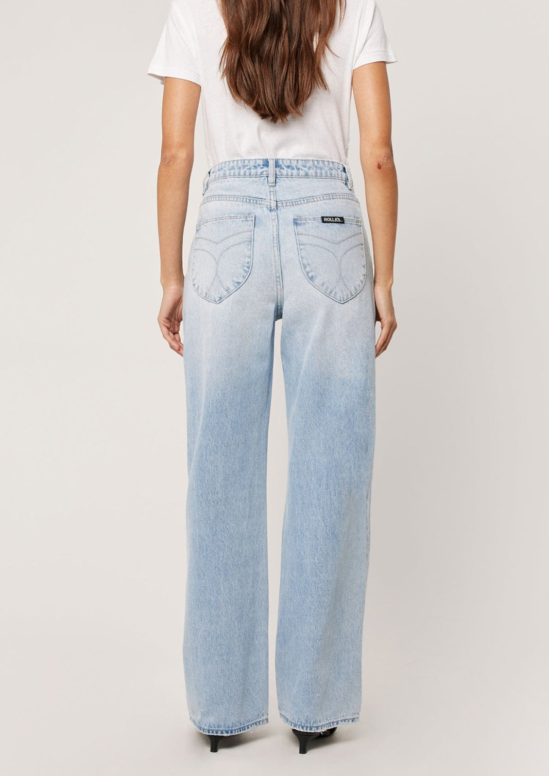 A person wearing a pair of straight leg relaxed jeans in light blue denim.