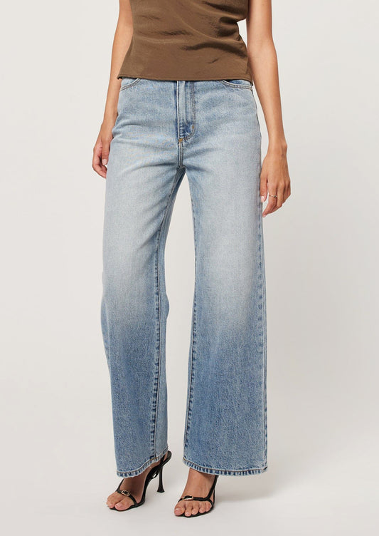 A person wearing a pair of wide leg blue jeans.