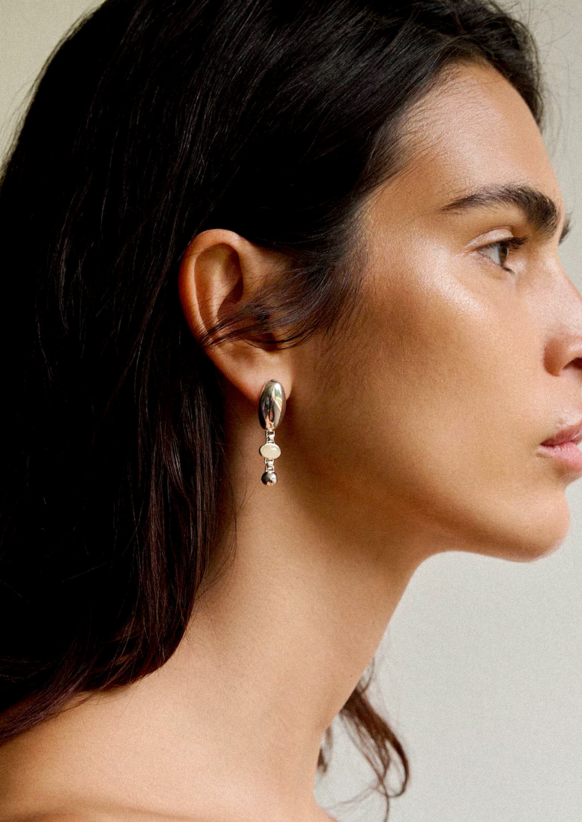 A pair of high shine silver earrings with honey topaz stone at center.