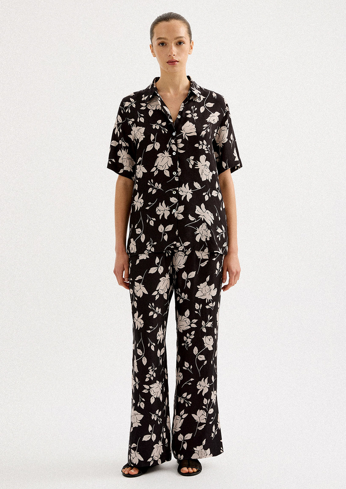 A person wearing a pair of monochrome floral pants in black and white.