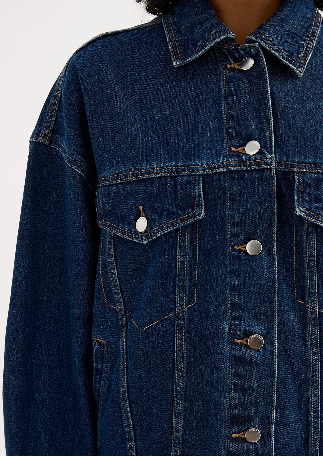 A woman wearing an oversized denim jacket in dark wash.