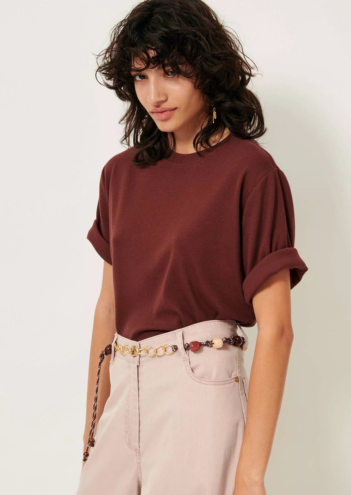 A woman wearing a short sleeve t-shirt with cuffs rolled up.